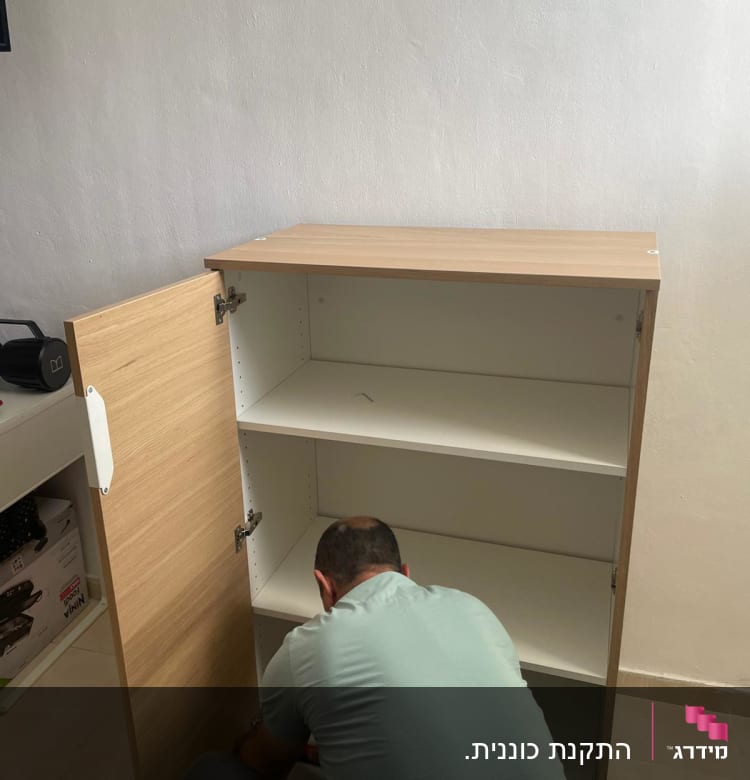 אדם מרכיב ארון עץ עם דלת פתוחה